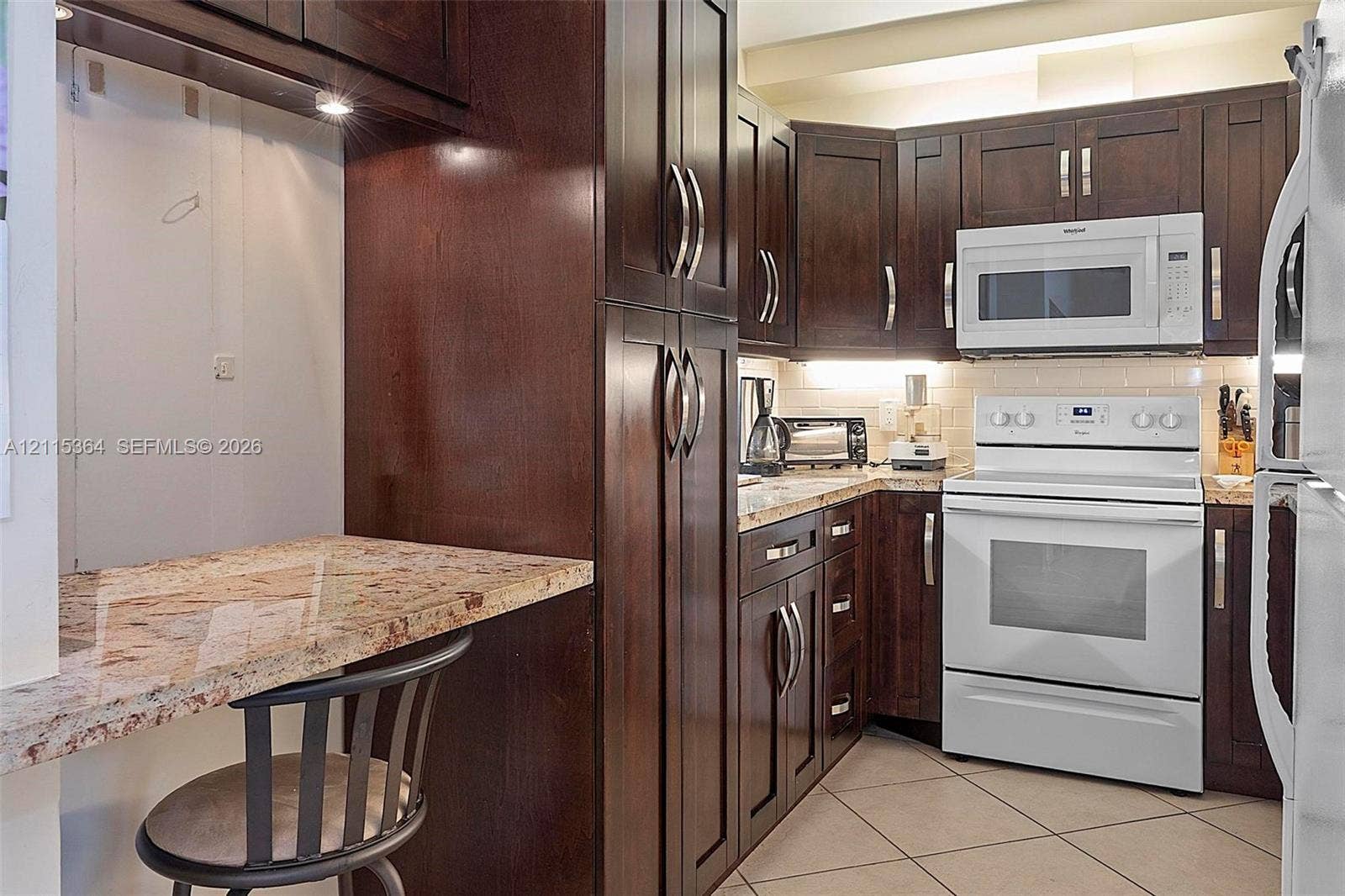 1980 S Ocean Drive, #20A, Hallandale Beach, Hallandale Beach, FL 33009 Kitchen featuring dark wood cabinetry, stone countertops, tiled flooring, under-cabinet lighting, and built-in appliances