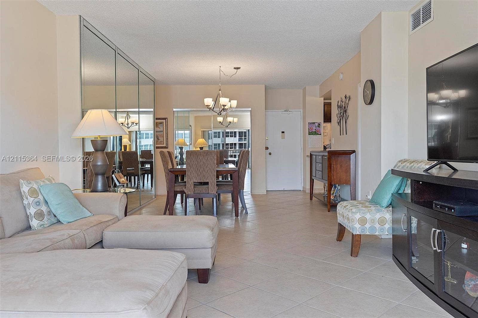 1980 S Ocean Drive, #20A, Hallandale Beach, Hallandale Beach, FL 33009 Open-concept interior featuring large-format tile flooring, wall-to-wall mirrored closet doors, a multi-arm chandelier, and neutral wall tones