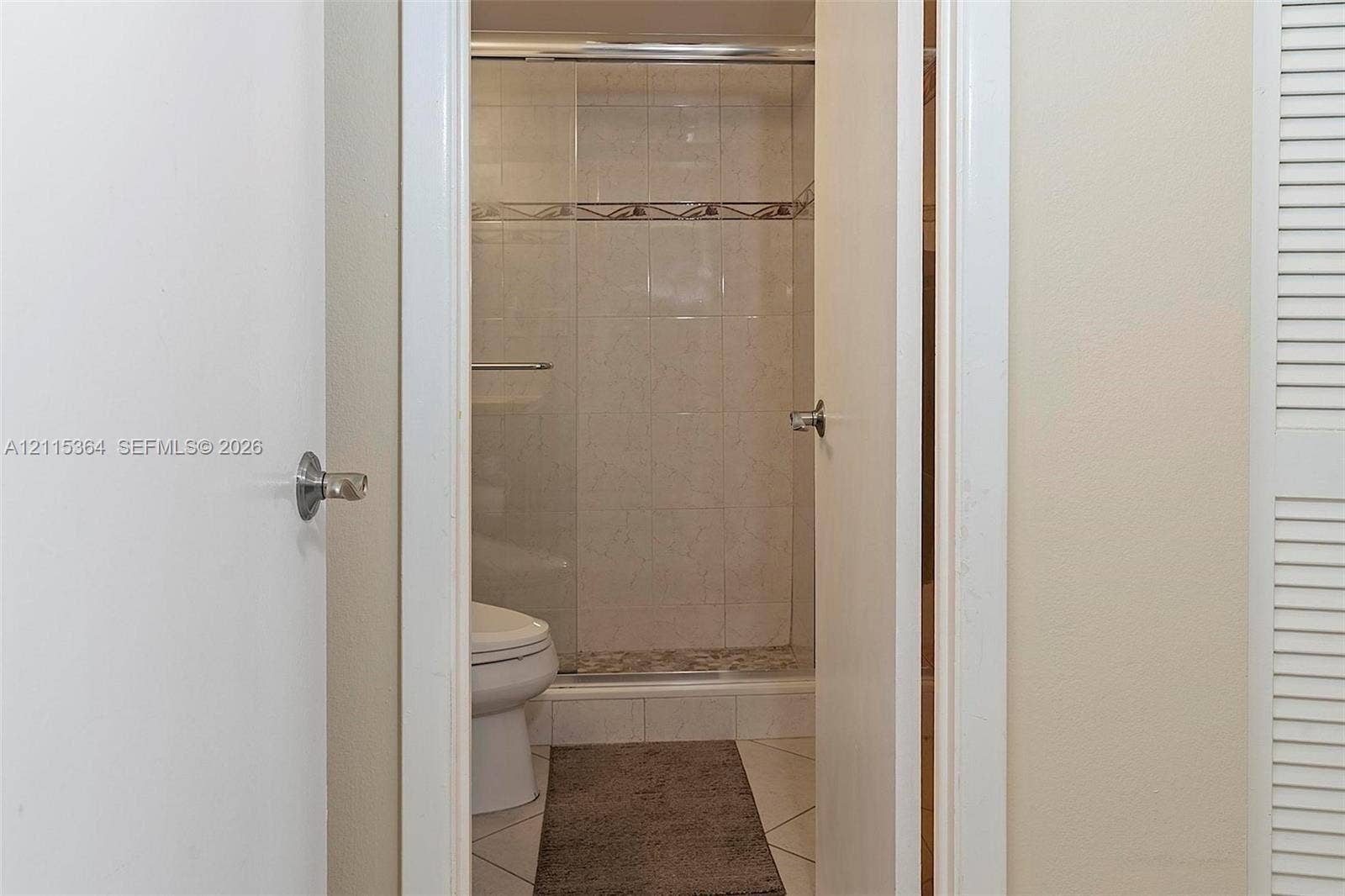 1980 S Ocean Drive, #20A, Hallandale Beach, Hallandale Beach, FL 33009 Bathroom featuring a glass-enclosed shower, light-toned wall tiling with decorative accent trim, and light-toned tile flooring