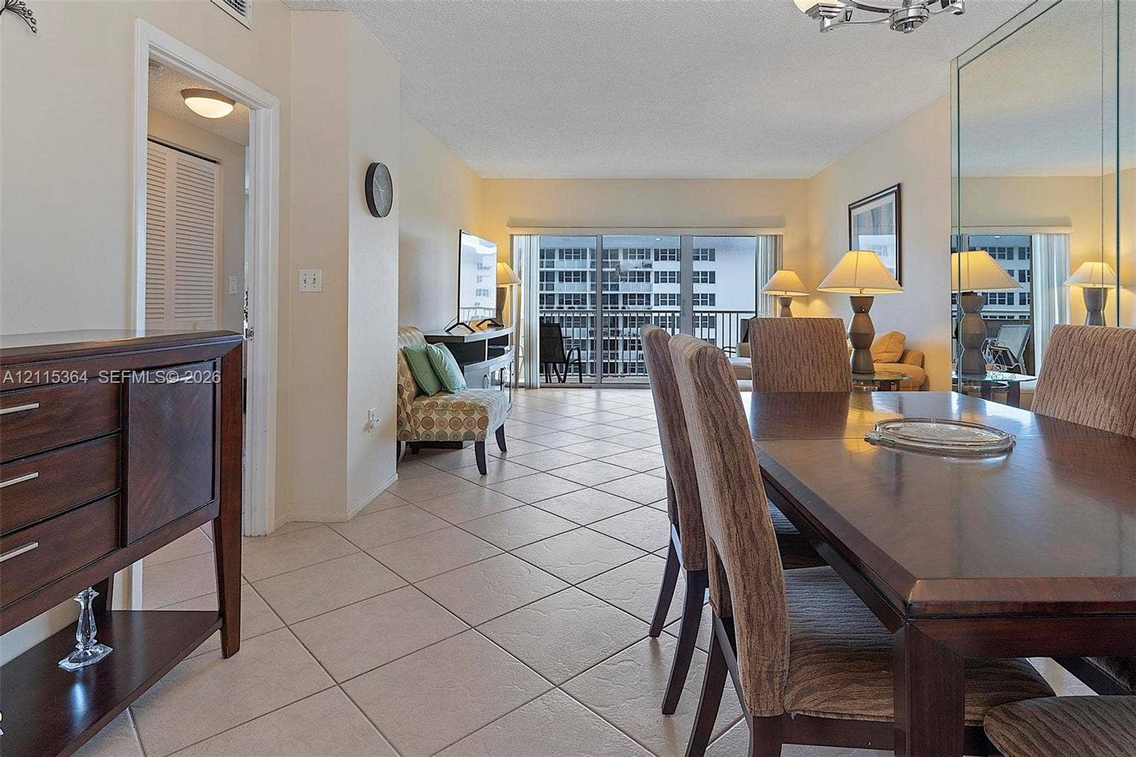 1980 S Ocean Drive, #20A, Hallandale Beach, Hallandale Beach, FL 33009 Open-concept living space featuring neutral ceramic tile flooring, floor-to-ceiling mirrored wall panels, sliding glass balcony doors, and recessed ceiling lighting
