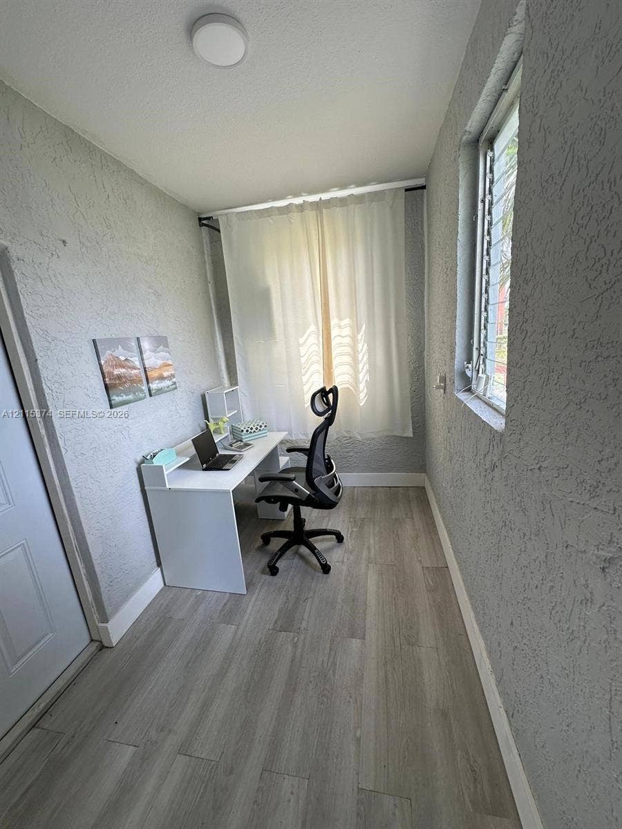 Room featuring textured wall finishes, wood-finish flooring, and a jalousie window