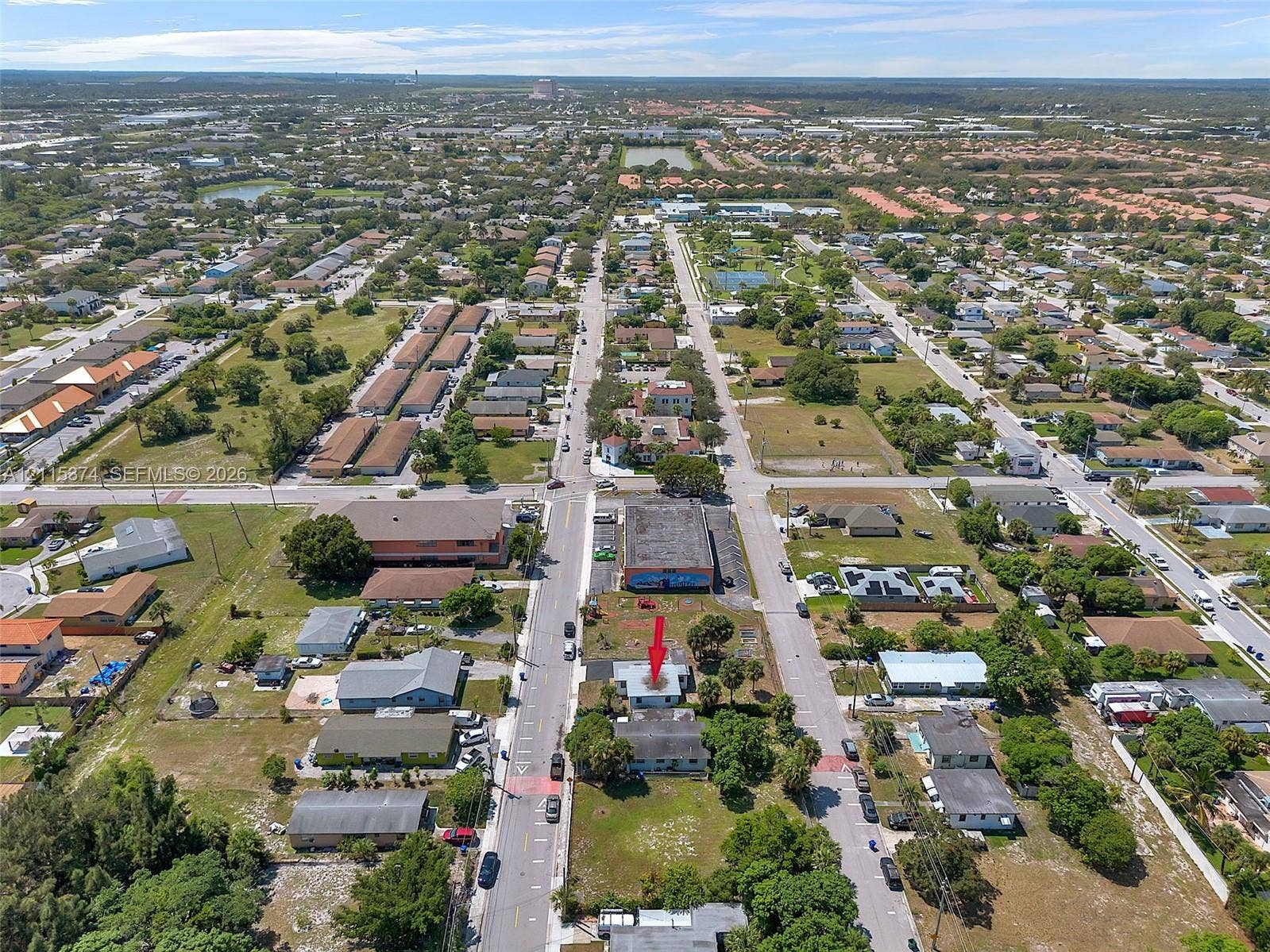 Aerial perspective of a corner lot property situated within an established residential grid, featuring paved street access and mature perimeter vegetation