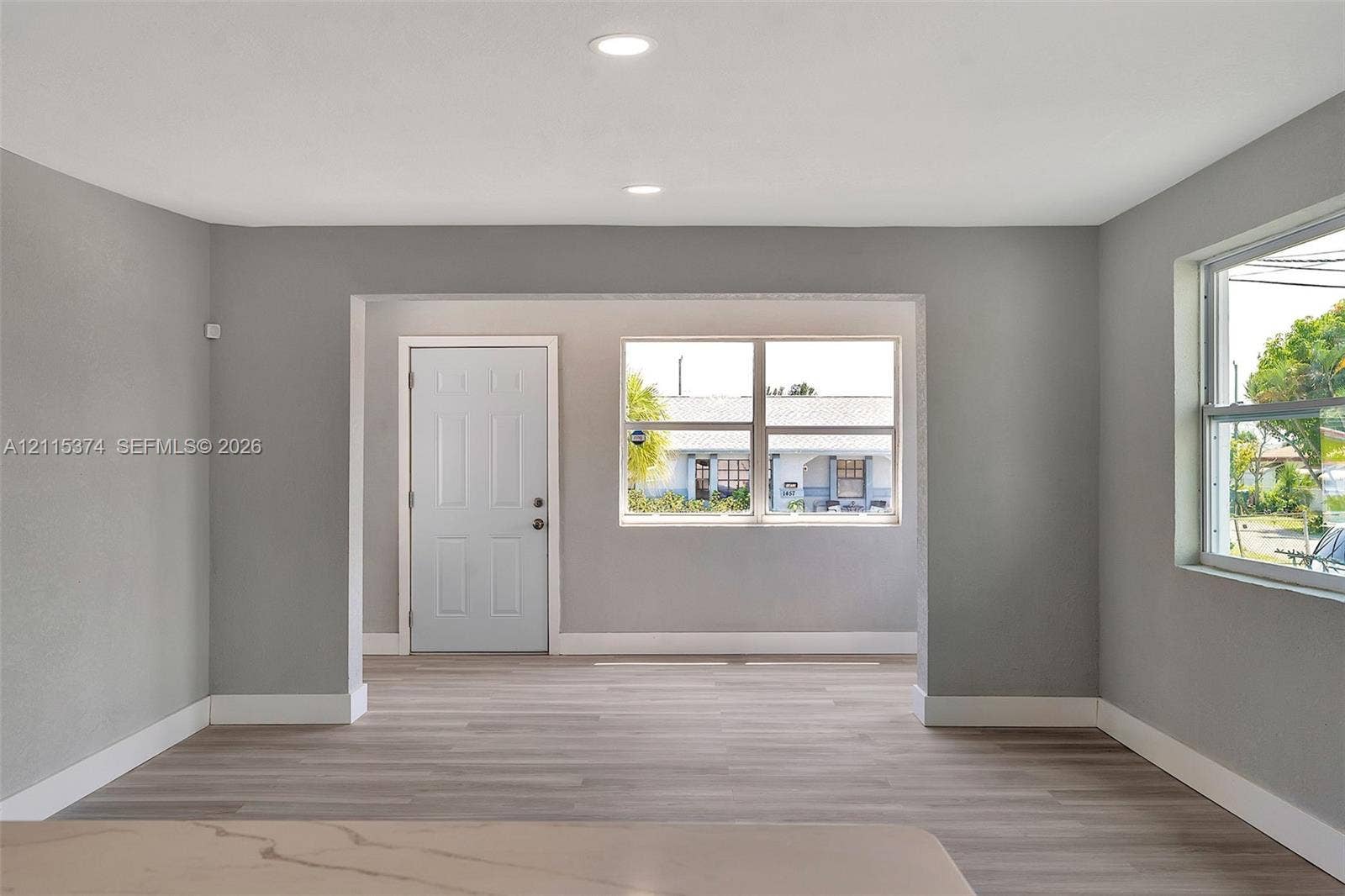 Interior space featuring neutral gray walls, wood-finish flooring, recessed lighting, and dual-pane windows
