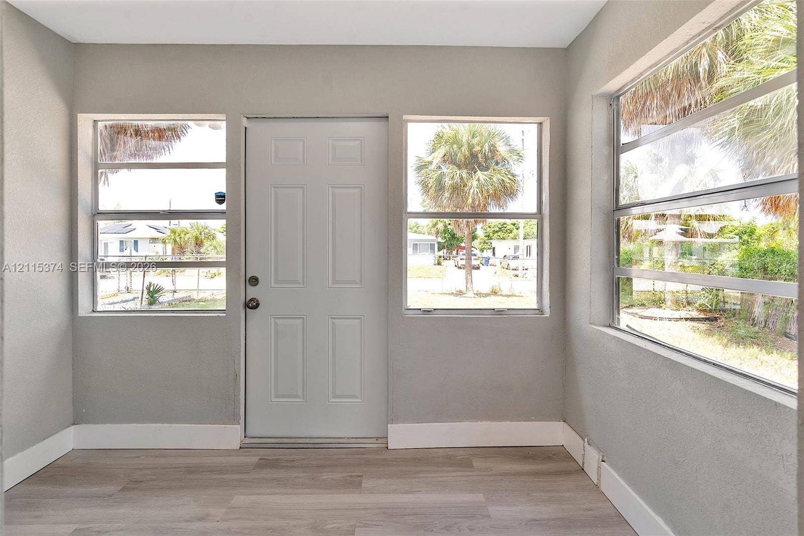 Interior entry featuring wood-finish flooring, multi-pane horizontal sliding windows, and a solid-core paneled entry door