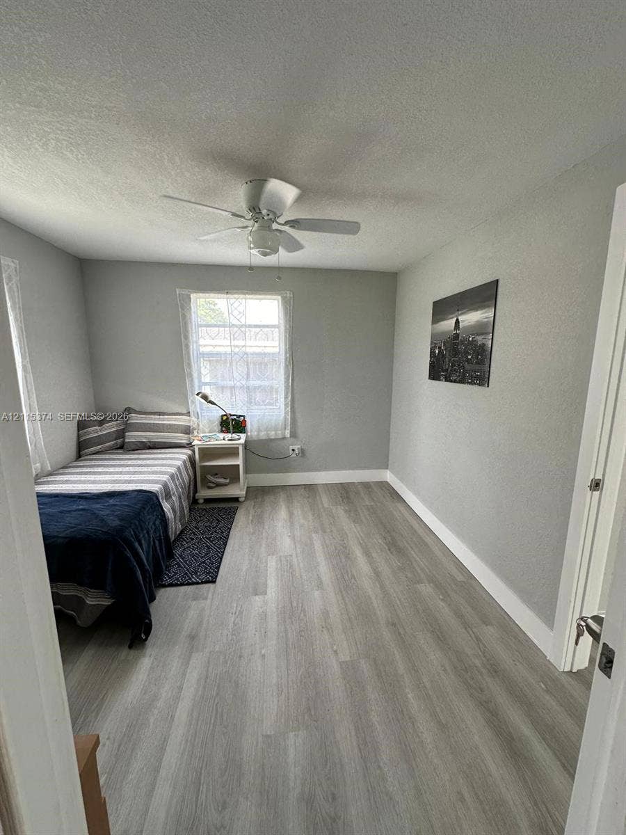 Wood-finish flooring, neutral wall tones, and ceiling fan fixture