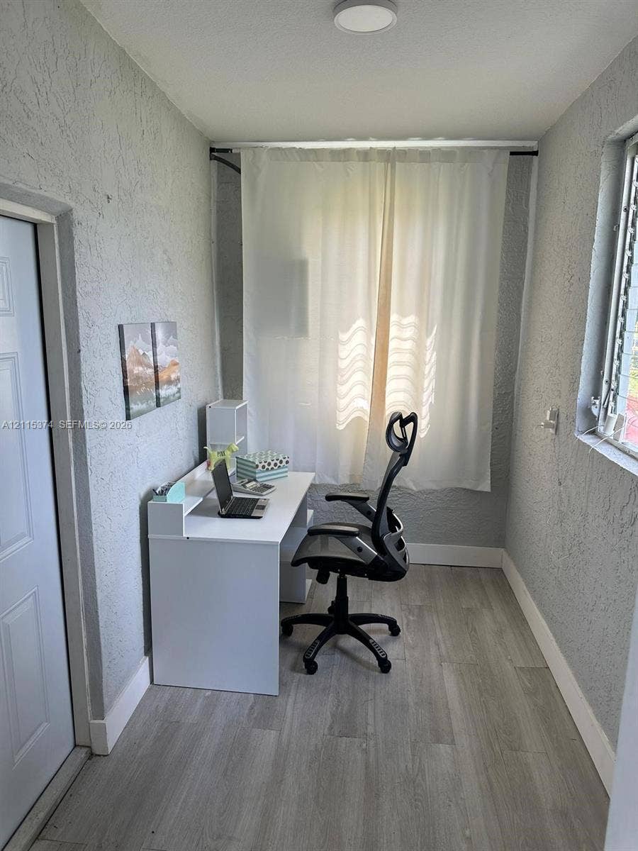 Textured grey walls, wood-finish flooring, and recessed ceiling lighting