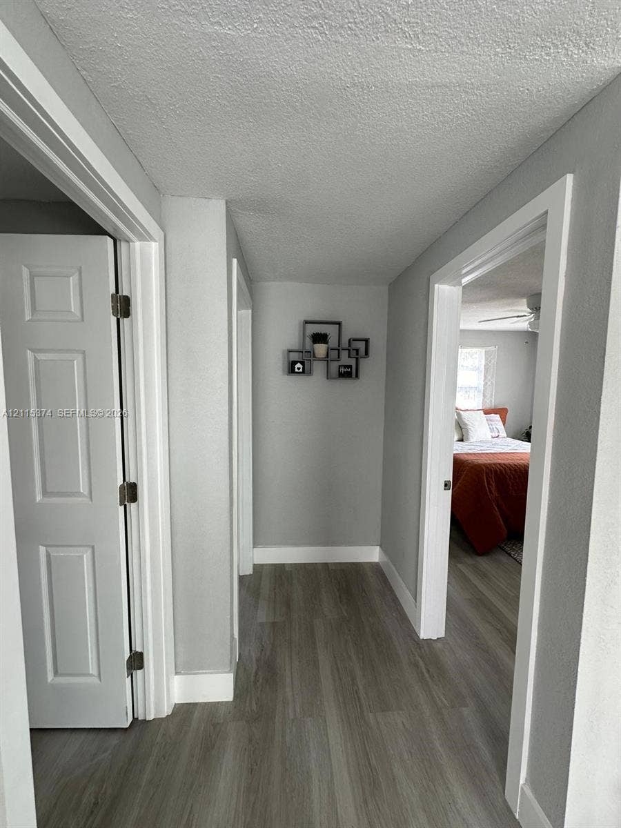 Hallway featuring neutral-toned walls, wood-finish flooring, and crisp white door casings with four-panel interior doors