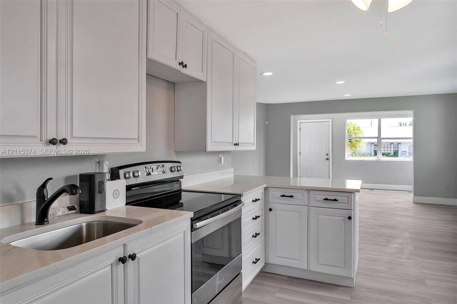 Kitchen featuring white shaker-style cabinetry, light-toned stone-finish countertops, stainless steel appliance suite, recessed lighting, and wood-finish flooring