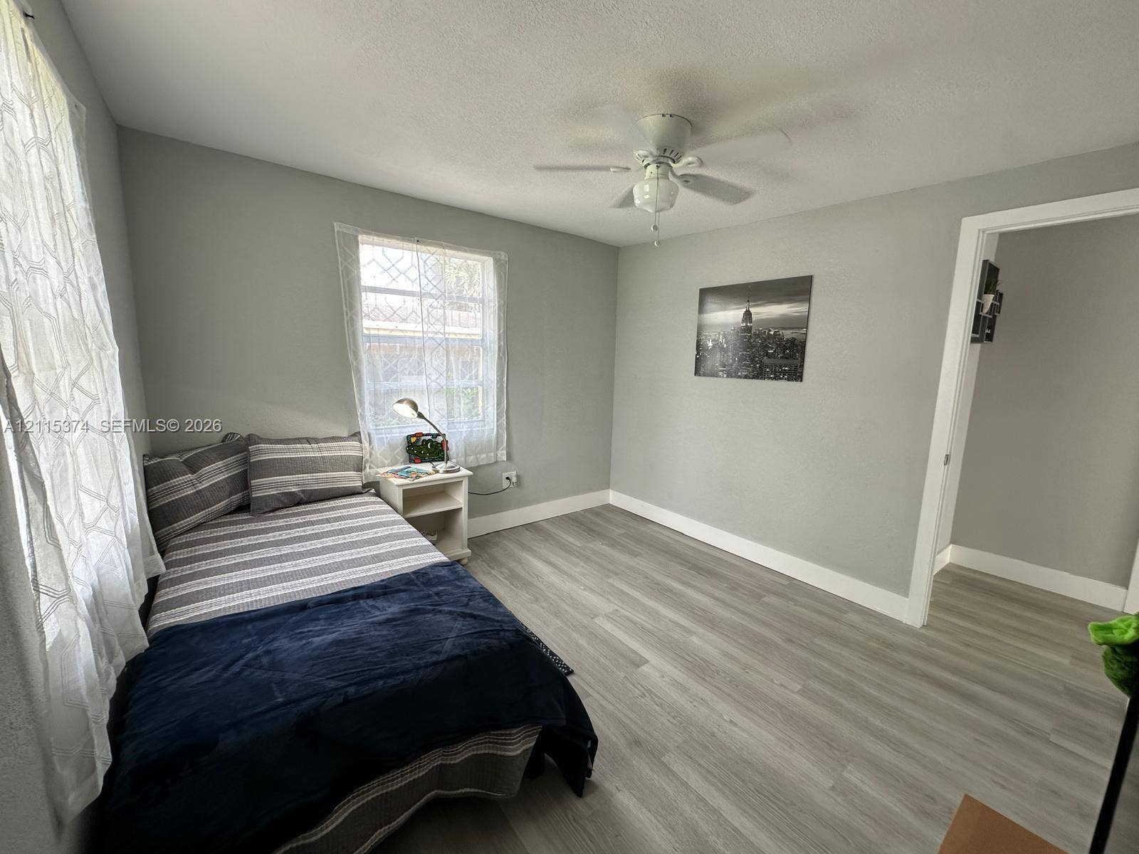 Interior space featuring light-toned wood-finish flooring, neutral wall paint, and a ceiling-mounted fan with integrated lighting