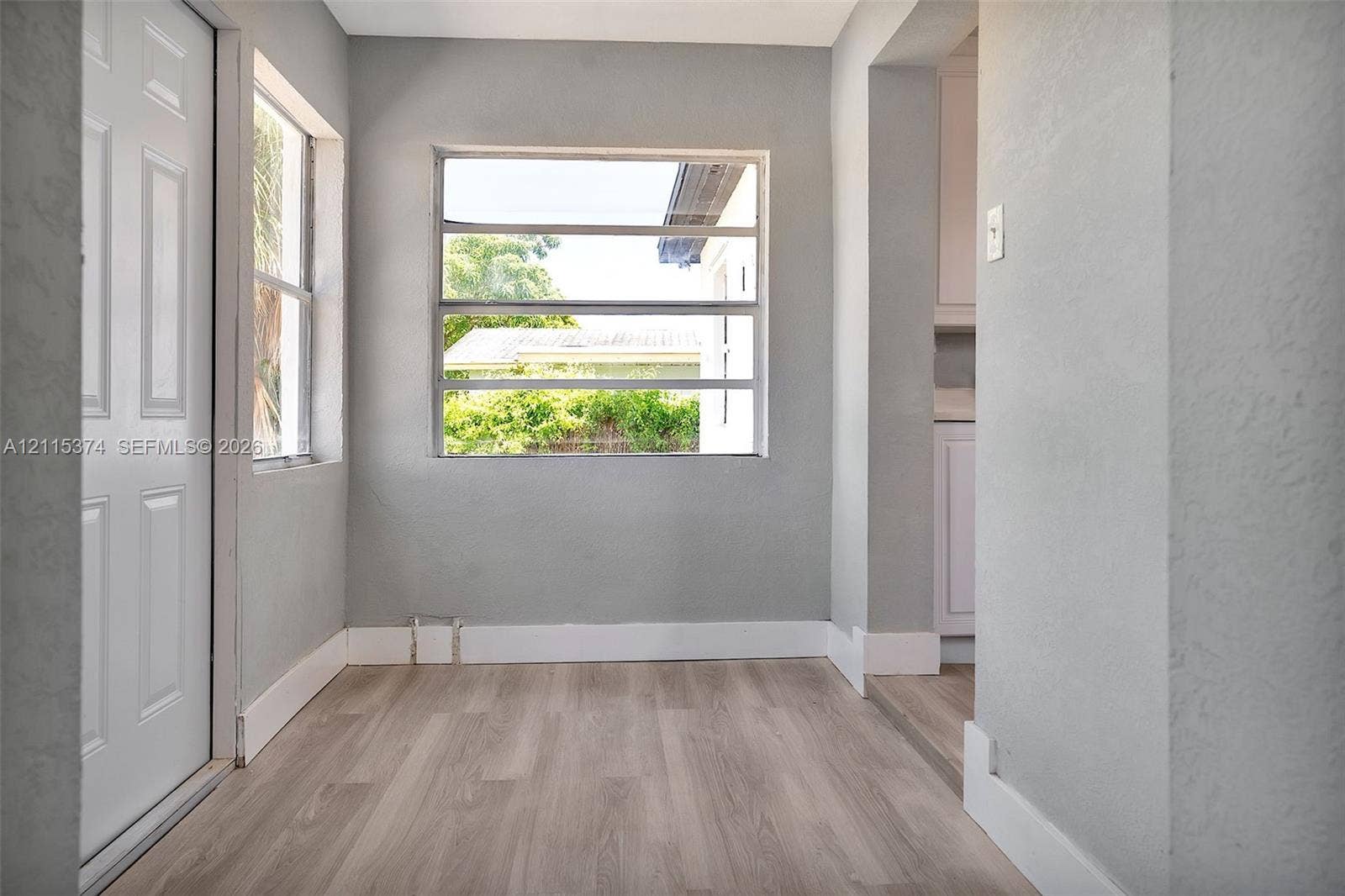 Neutral-toned interior featuring wood-finish flooring, crisp white trim, and multiple horizontal slider windows