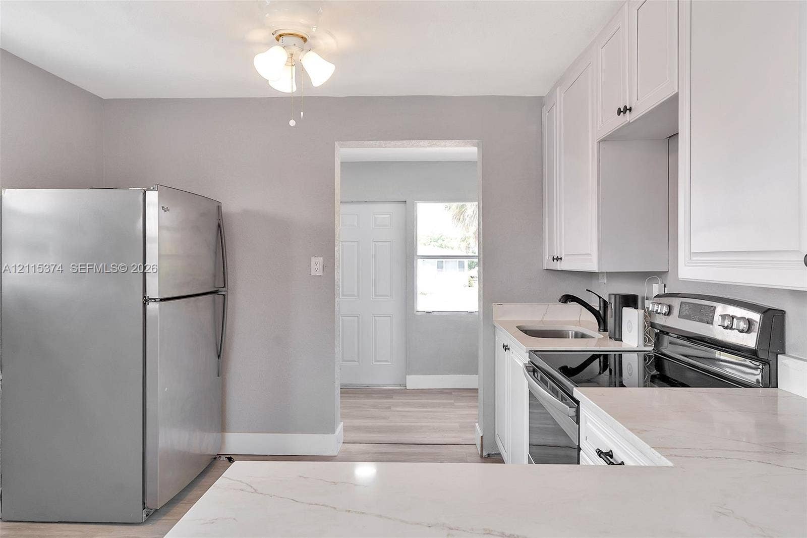 Kitchen featuring white shaker-style cabinetry, stone-finish countertops, stainless steel appliances, and wood-finish flooring