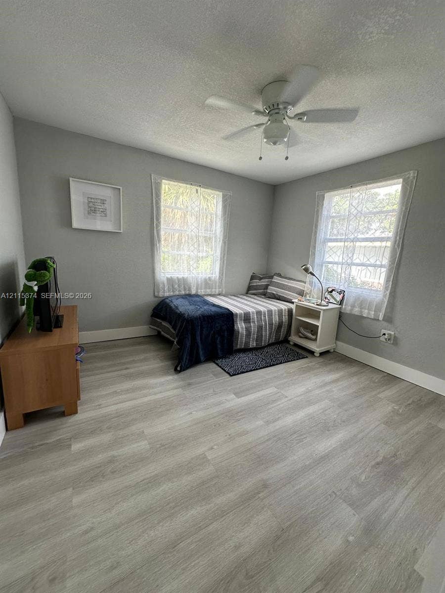 Room featuring wood-finish flooring, dual windows, and a ceiling fan