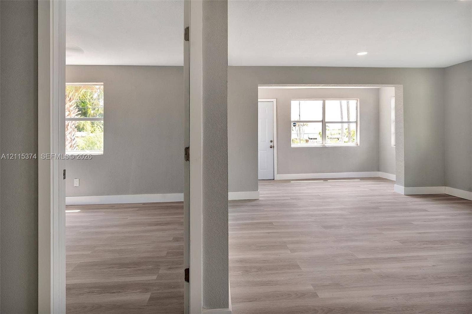 Interior space featuring light-tone wood-finish flooring, neutral wall paint, multi-pane windows, and recessed lighting