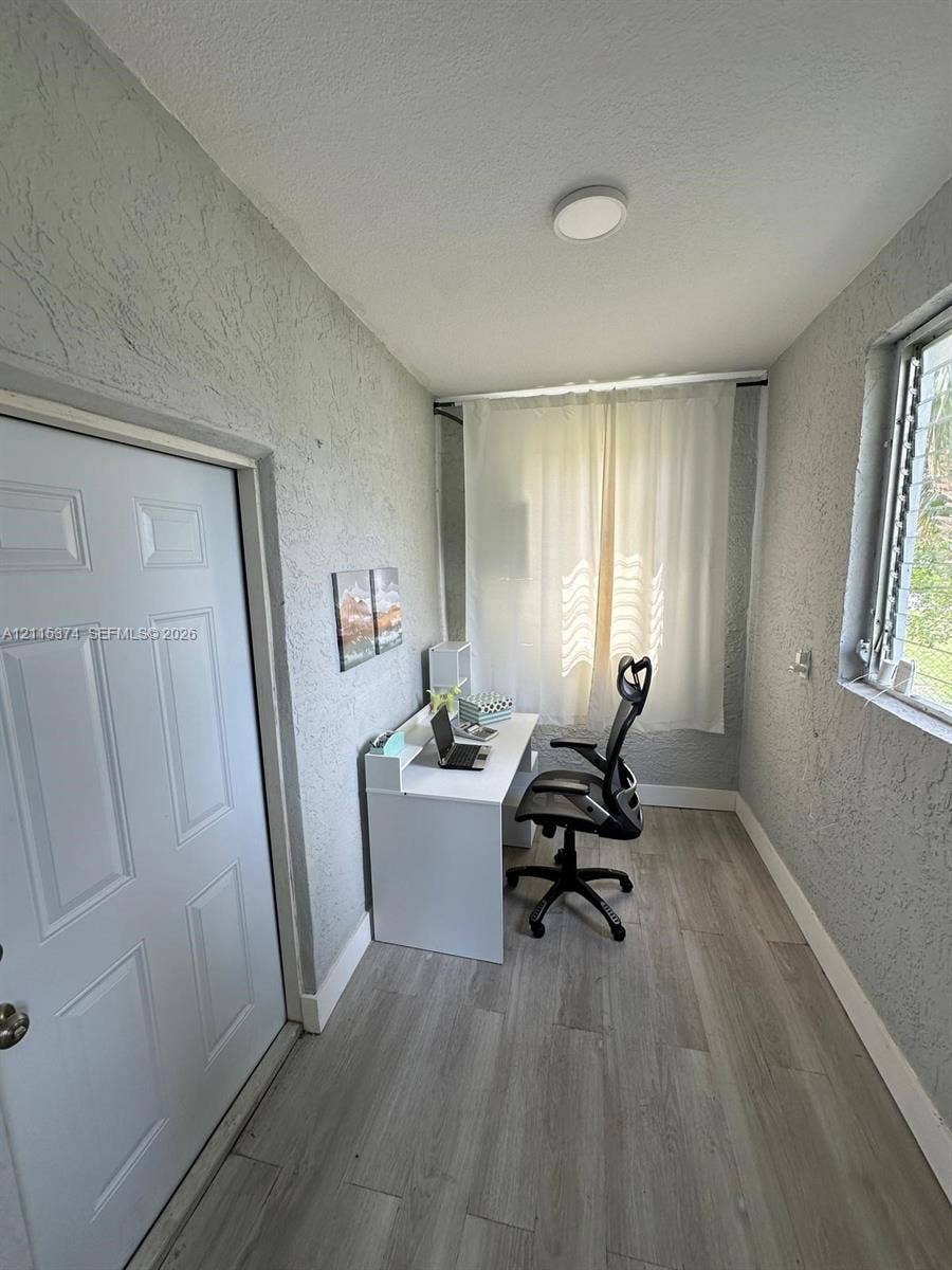 Textured walls, wood-finish flooring, and a single-pane window with a metal security grill