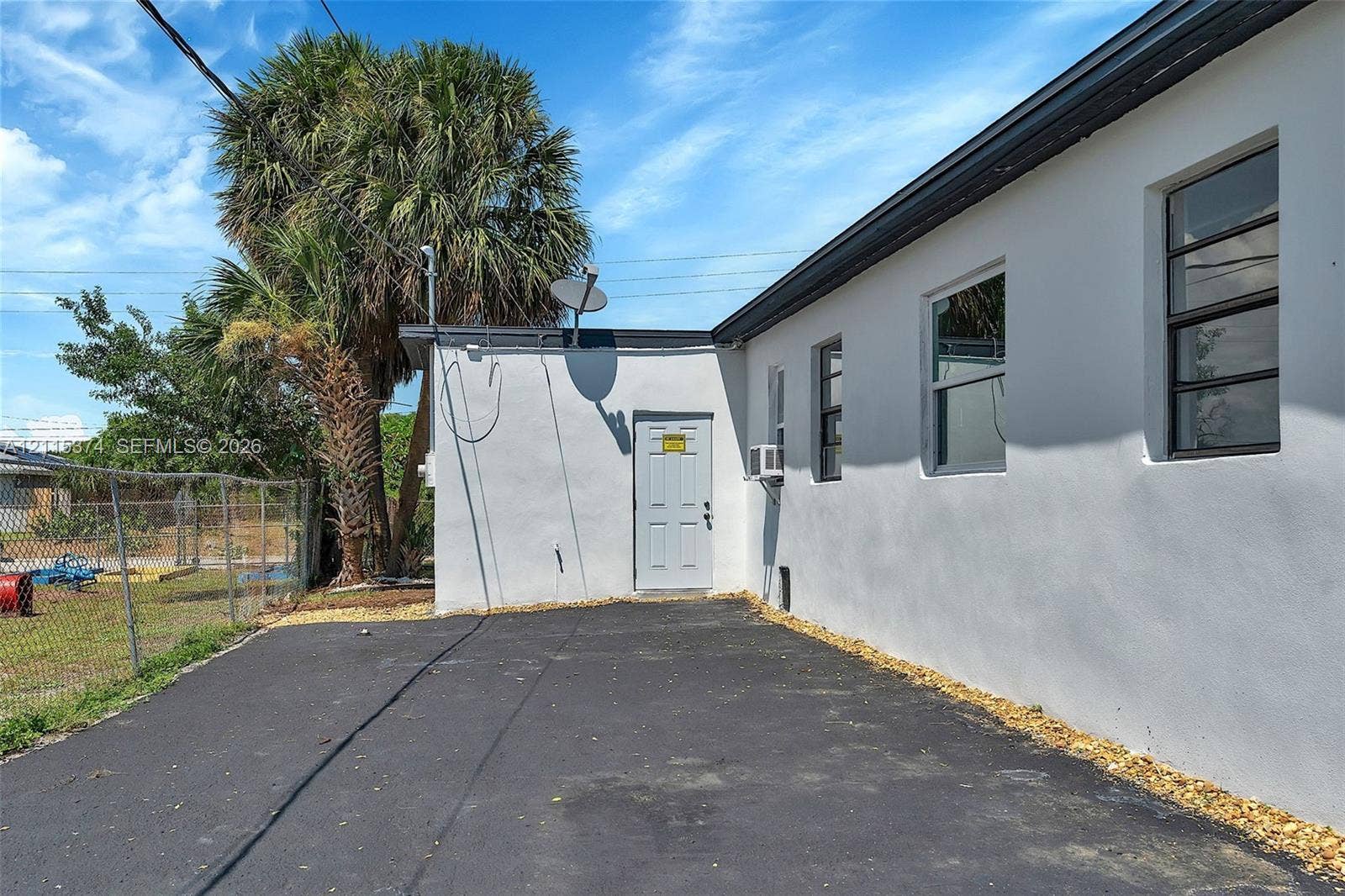 Exterior side elevation featuring a smooth stucco finish, asphalt paving, and metal-framed windows