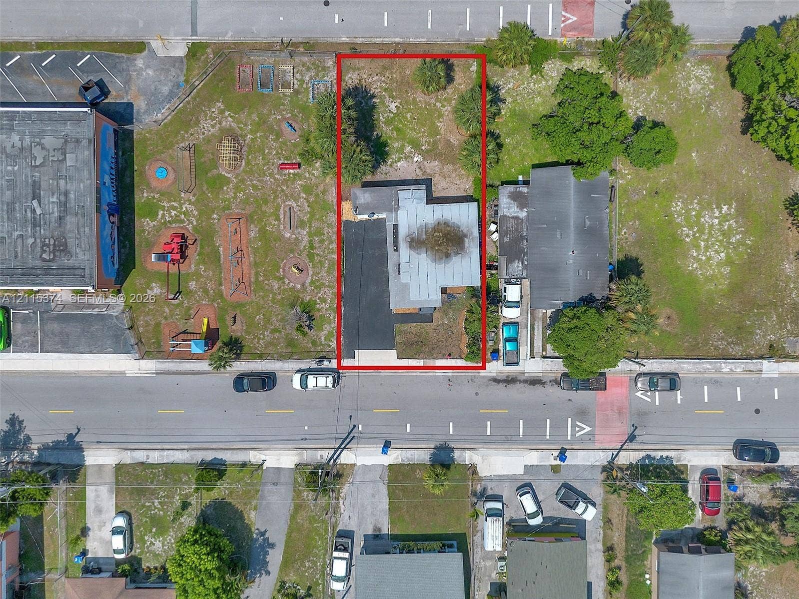 Aerial perspective of a rectangular lot featuring a single-story structure, an asphalt driveway, and mature landscaping