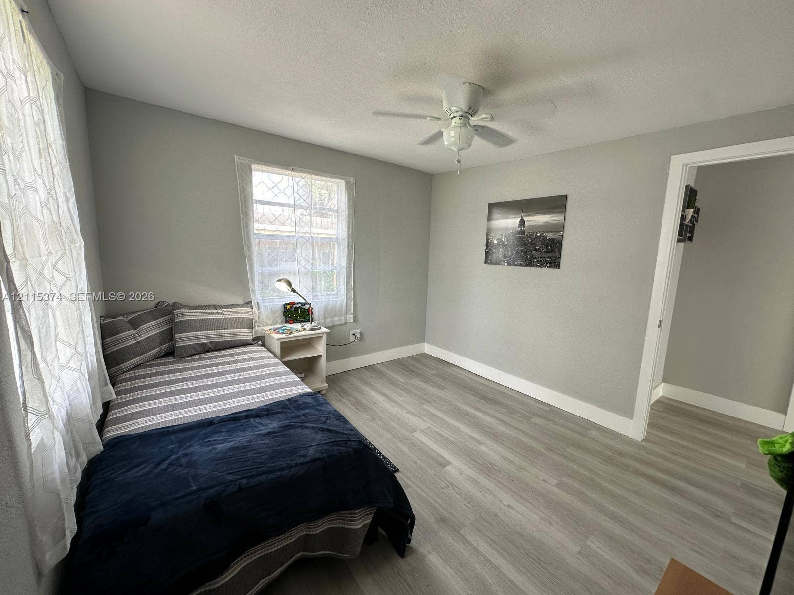 Neutral-toned interior featuring wood-finish flooring, white ceiling fan, and multi-pane window