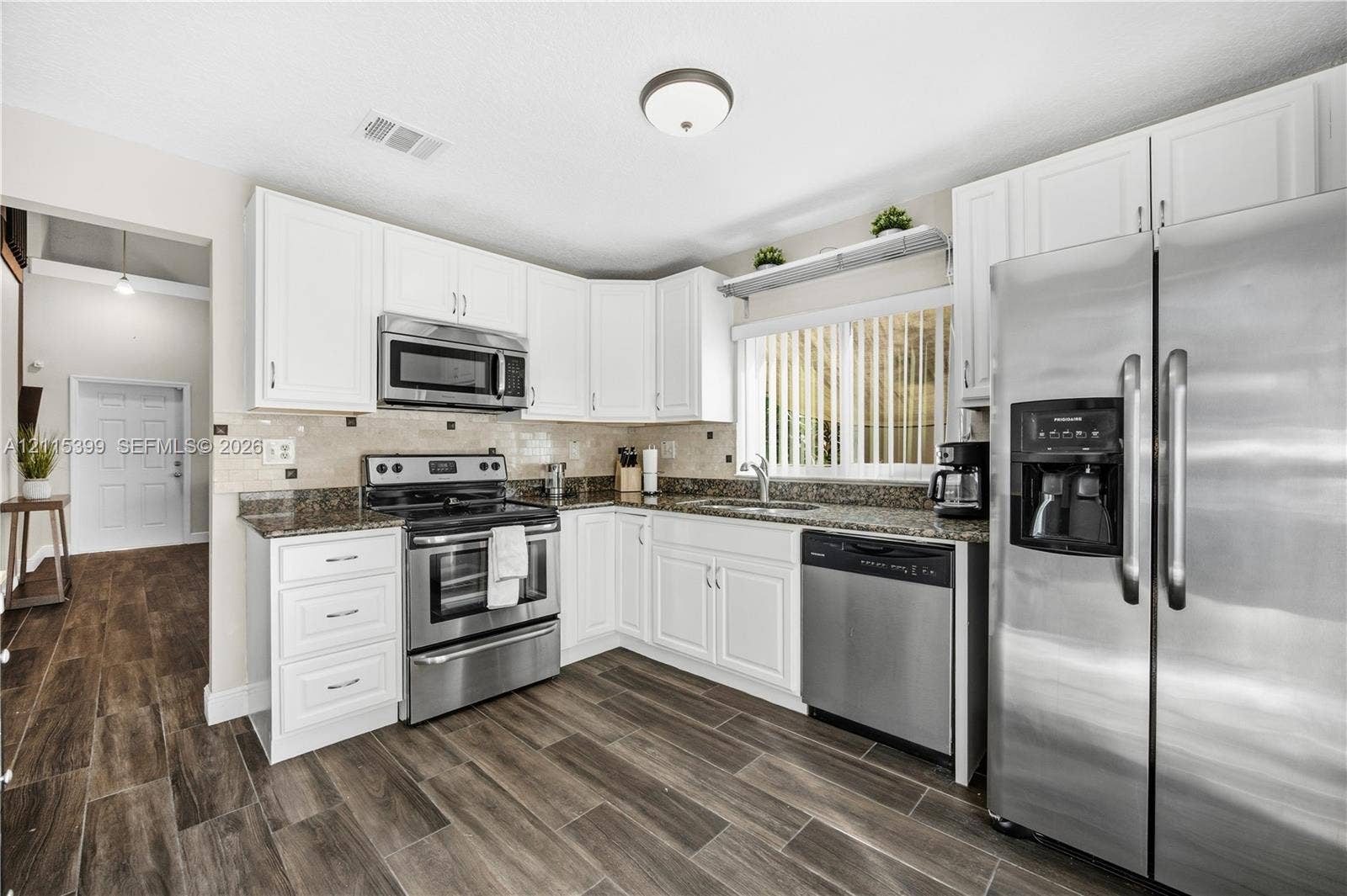 Kitchen featuring white cabinetry, stone-surface countertops, stainless steel appliances, and wood-finish flooring