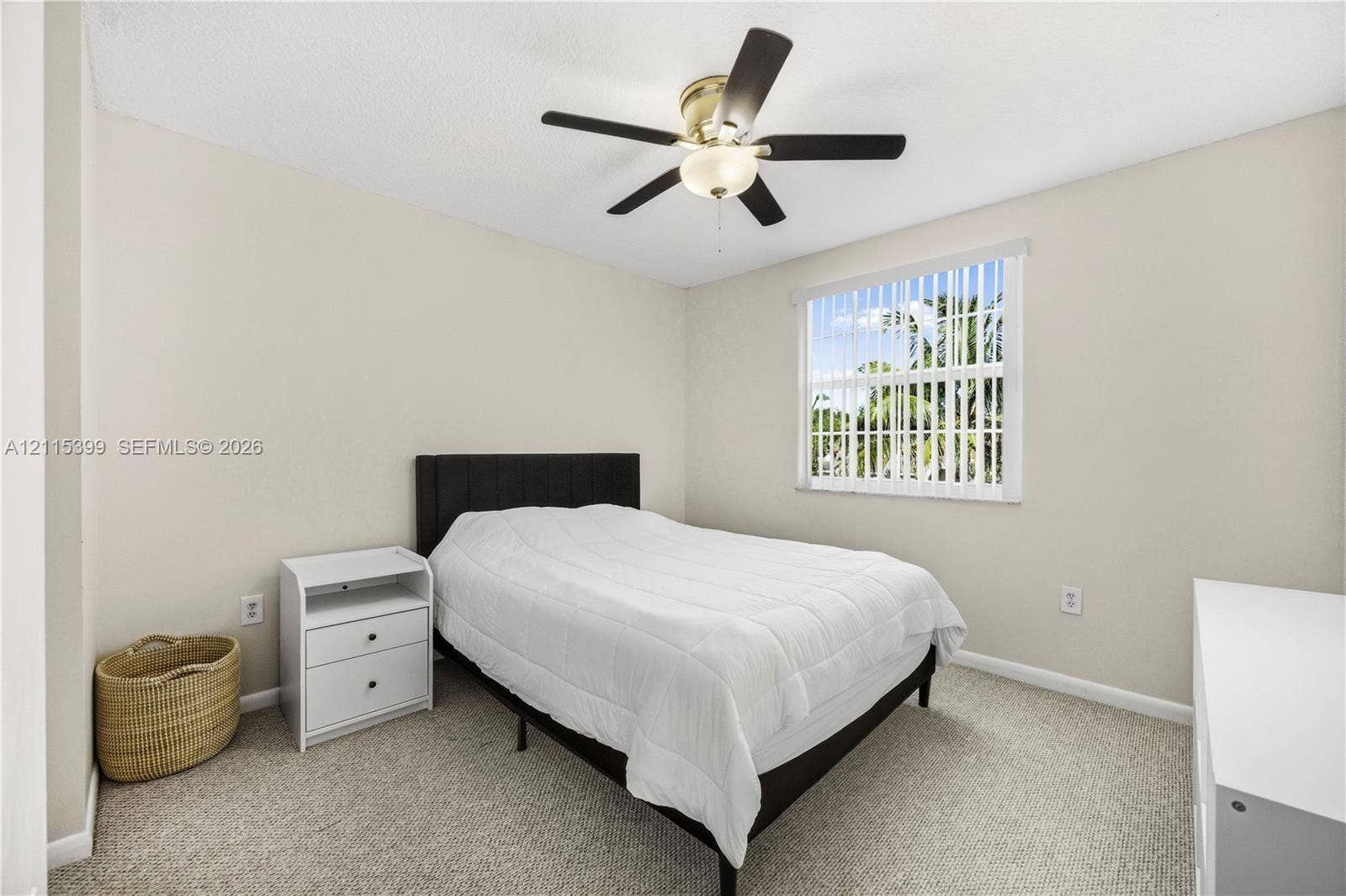 Neutral-toned walls, wall-to-wall carpeting, window with vertical blinds, and a ceiling fan with integrated lighting fixture