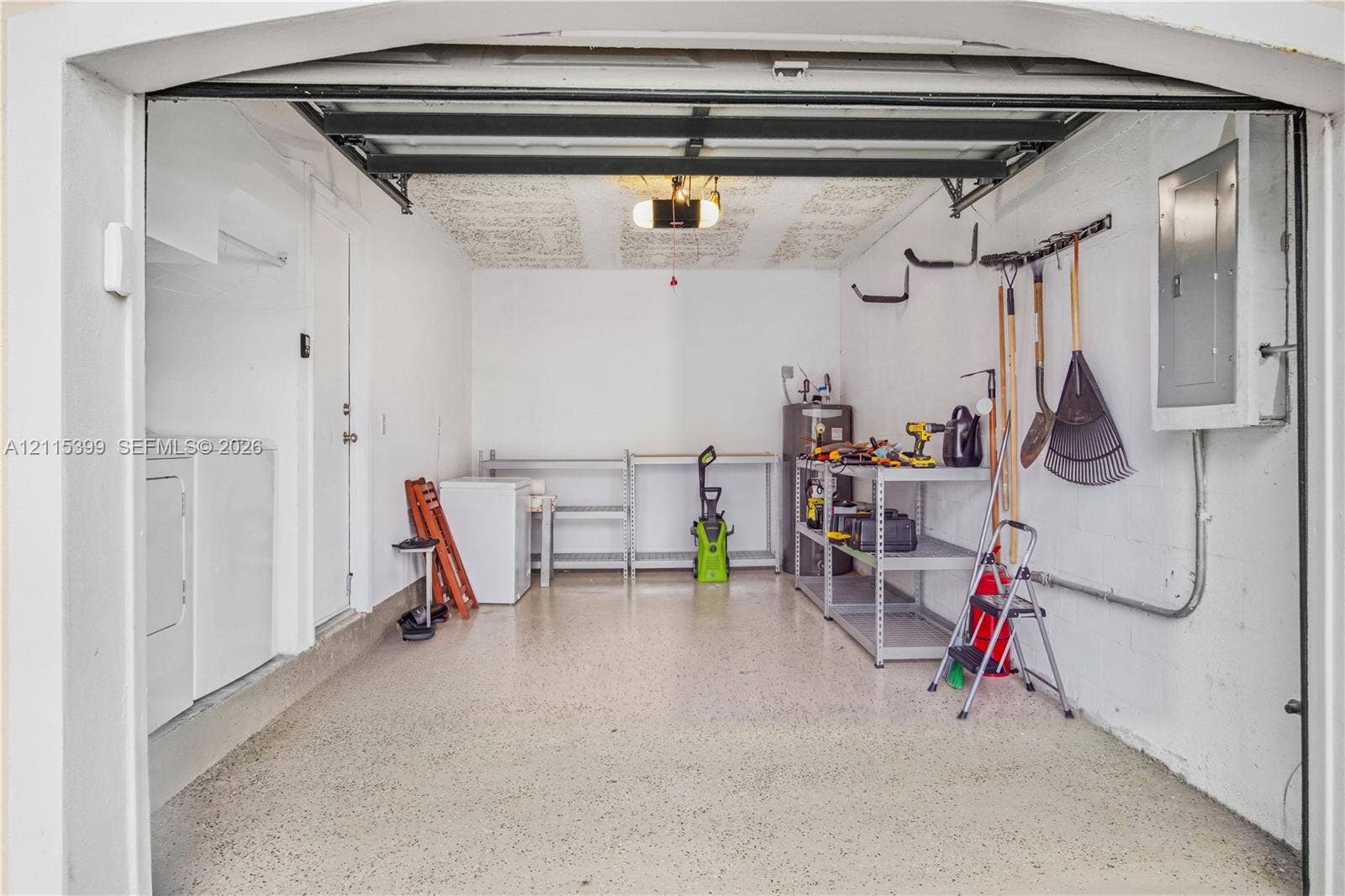 Garage featuring an epoxy-coated floor, built-in electrical panel, and dedicated laundry area with washer and dryer hookups