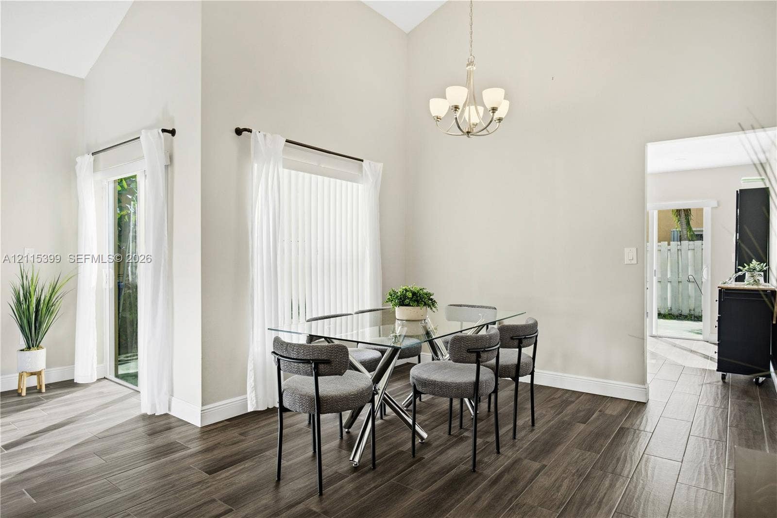 Vaulted ceilings, wood-finish tile flooring, glass sliding door, and a multi-arm chandelier