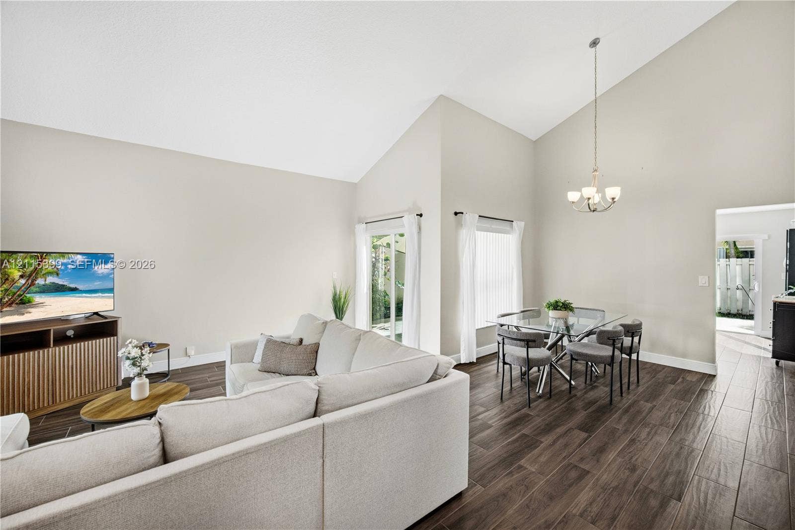 Vaulted ceilings, wood-finish tile flooring, and a multi-arm hanging chandelier