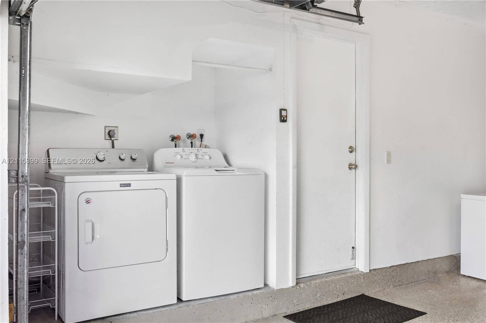 Laundry area featuring a dedicated recessed hookup space, an overhead built-in clothing rod, and a swinging utility door