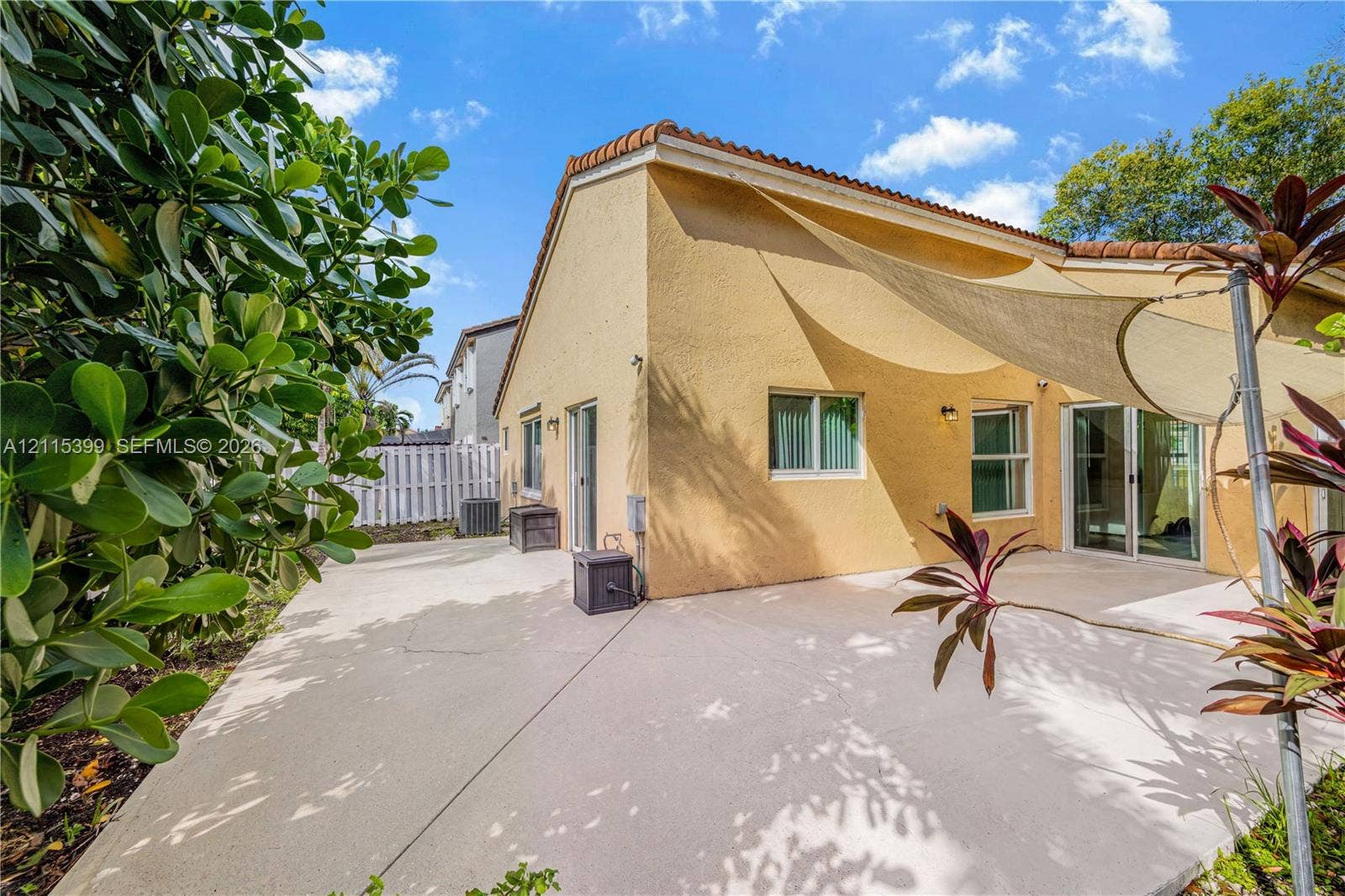 Stucco exterior featuring a concrete patio, sliding glass doors, and a tile roof