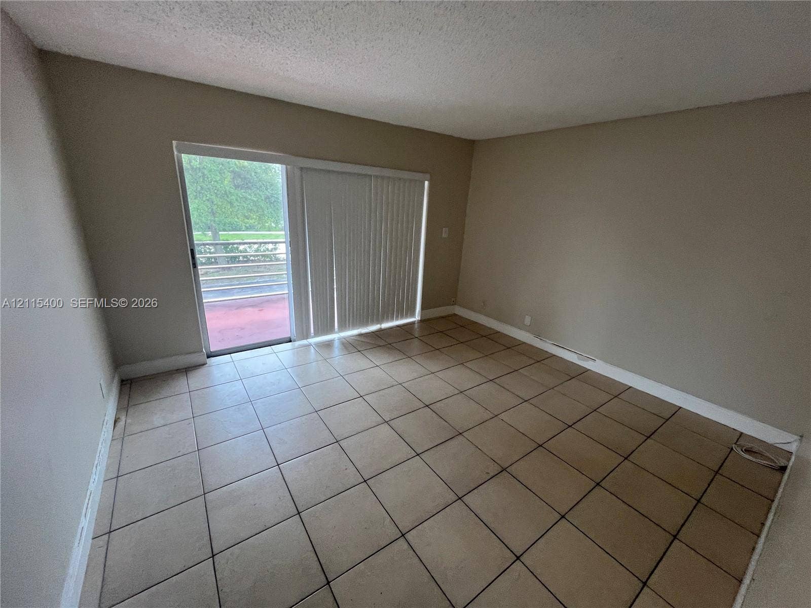 Interior space featuring ceramic tile flooring and sliding glass doors with vertical blinds