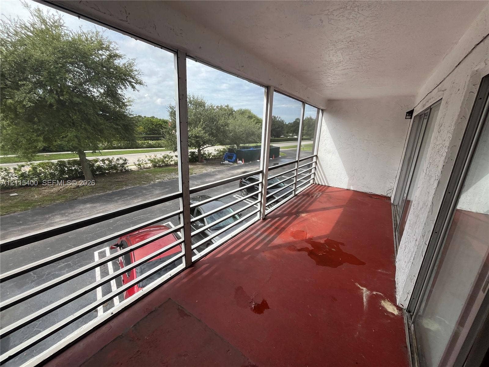 Screened-in balcony featuring a metal railing and sliding glass door access