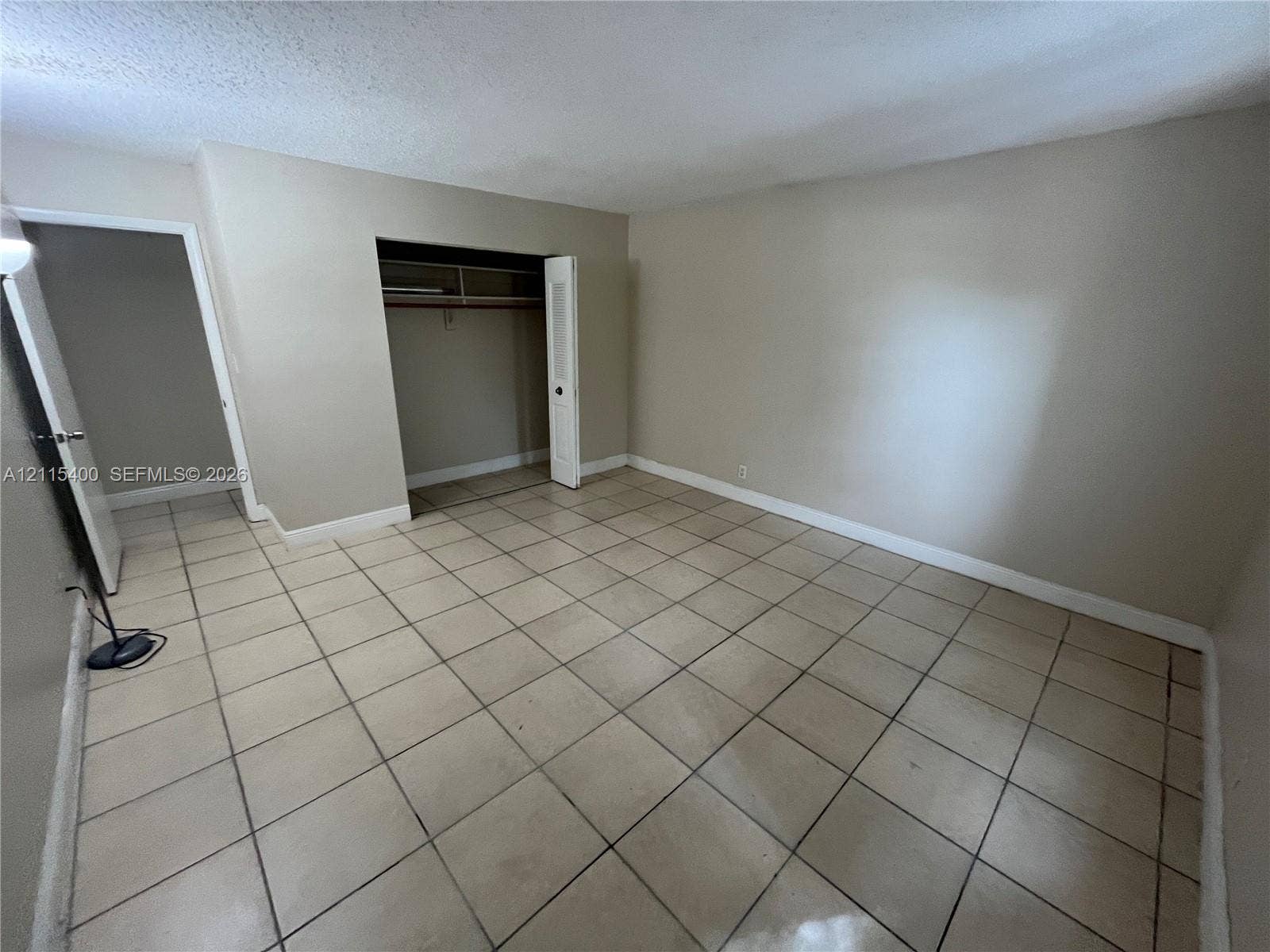 Room featuring large-format square tile flooring and a built-in closet with louvered double doors