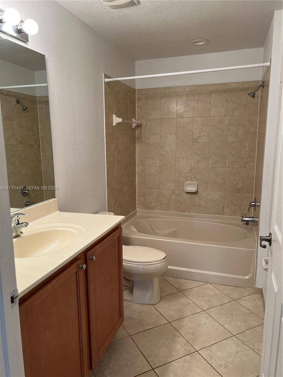 11503 NW 89th Street, #104, Doral, Doral, FL 33178 Bathroom featuring a vanity with a solid-surface countertop, ceramic tile flooring, a tub-shower combination with full-height tile surround, and a wall-mounted mirror with integrated lighting