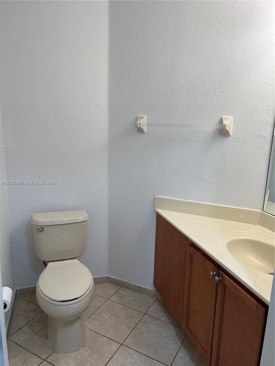 11503 NW 89th Street, #104, Doral, Doral, FL 33178 Vanity featuring wood cabinetry, a solid surface countertop with an integrated sink, and ceramic tile flooring