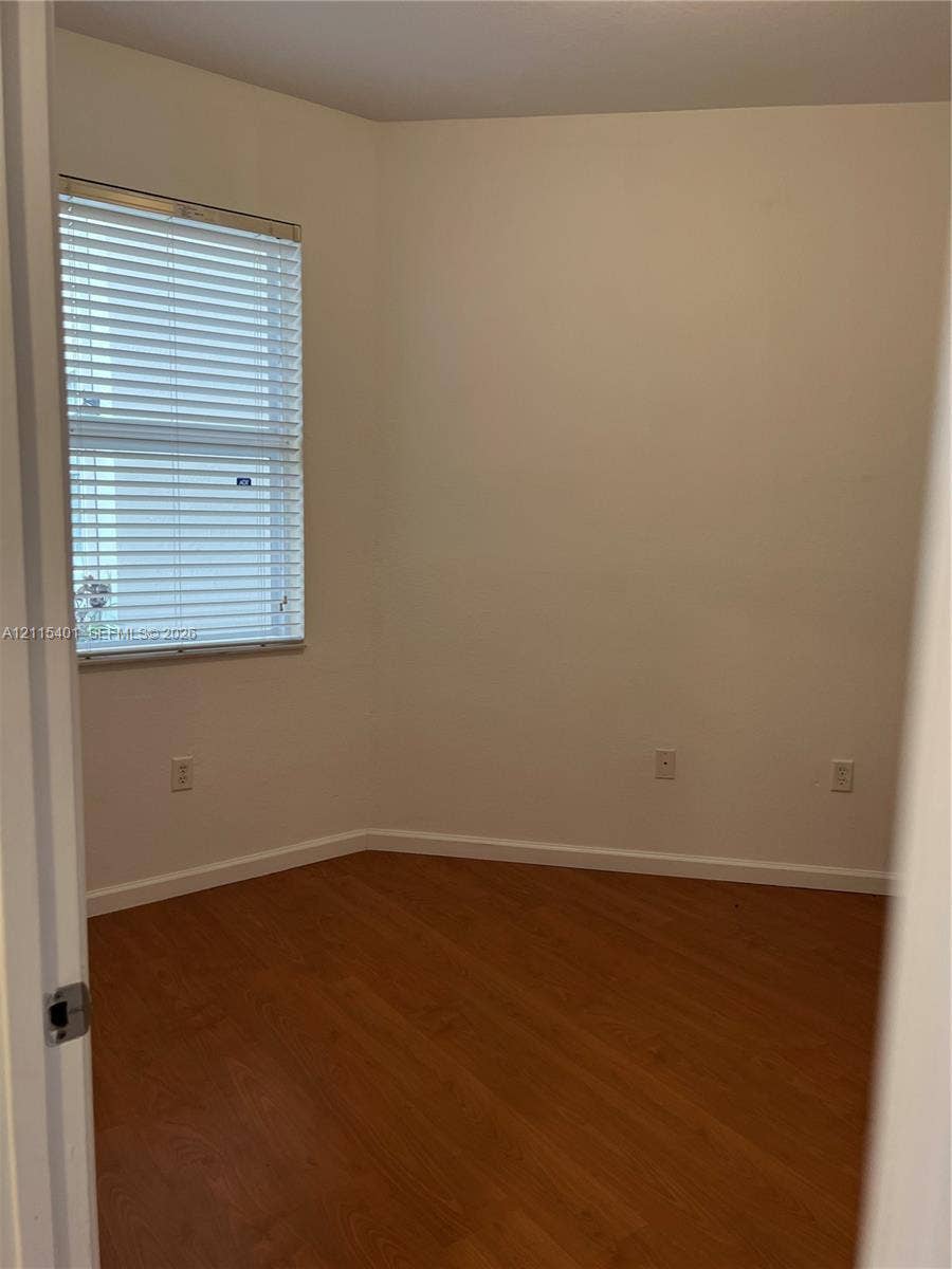 11503 NW 89th Street, #104, Doral, Doral, FL 33178 Neutral-toned room featuring wood-finish flooring and a window with horizontal blinds