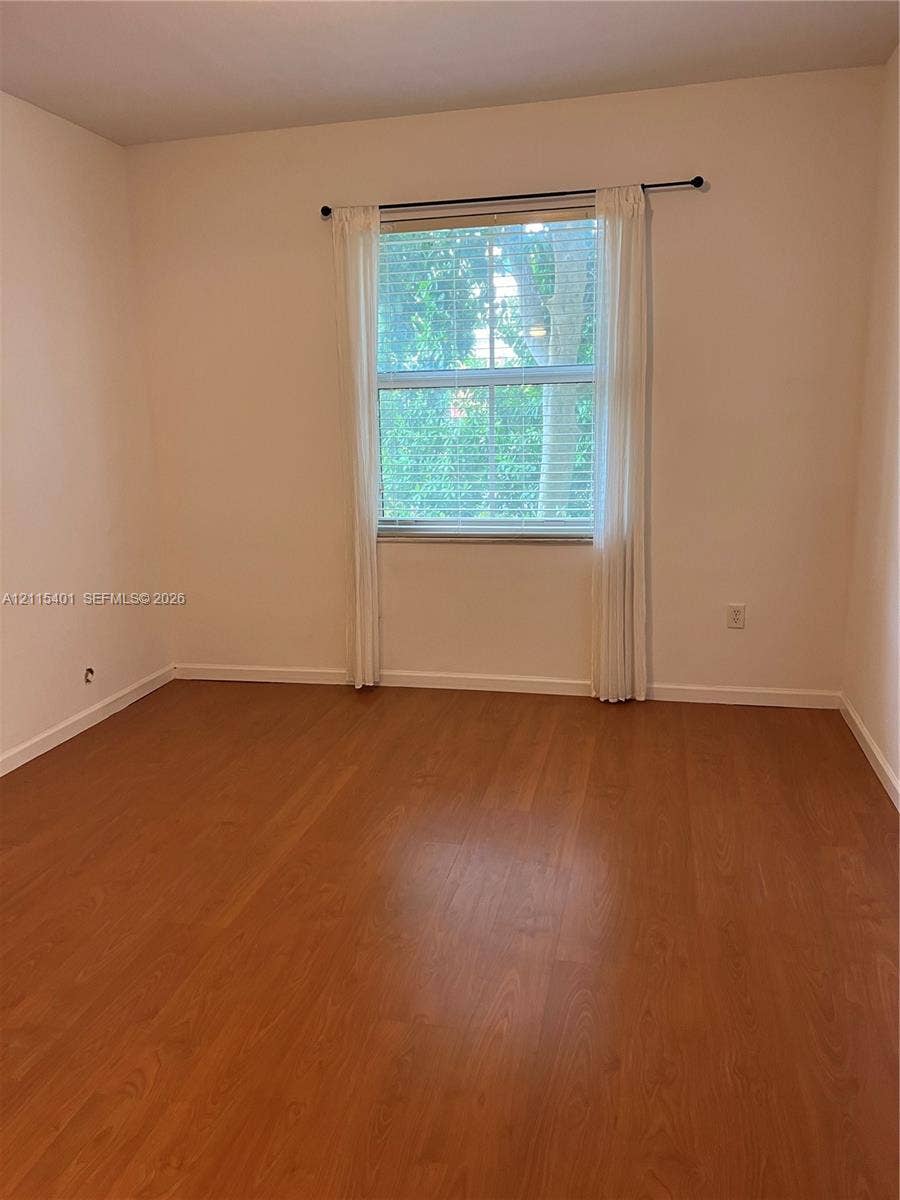 11503 NW 89th Street, #104, Doral, Doral, FL 33178 Interior room featuring wood-finish flooring, neutral wall tones, and a single window with integrated blinds