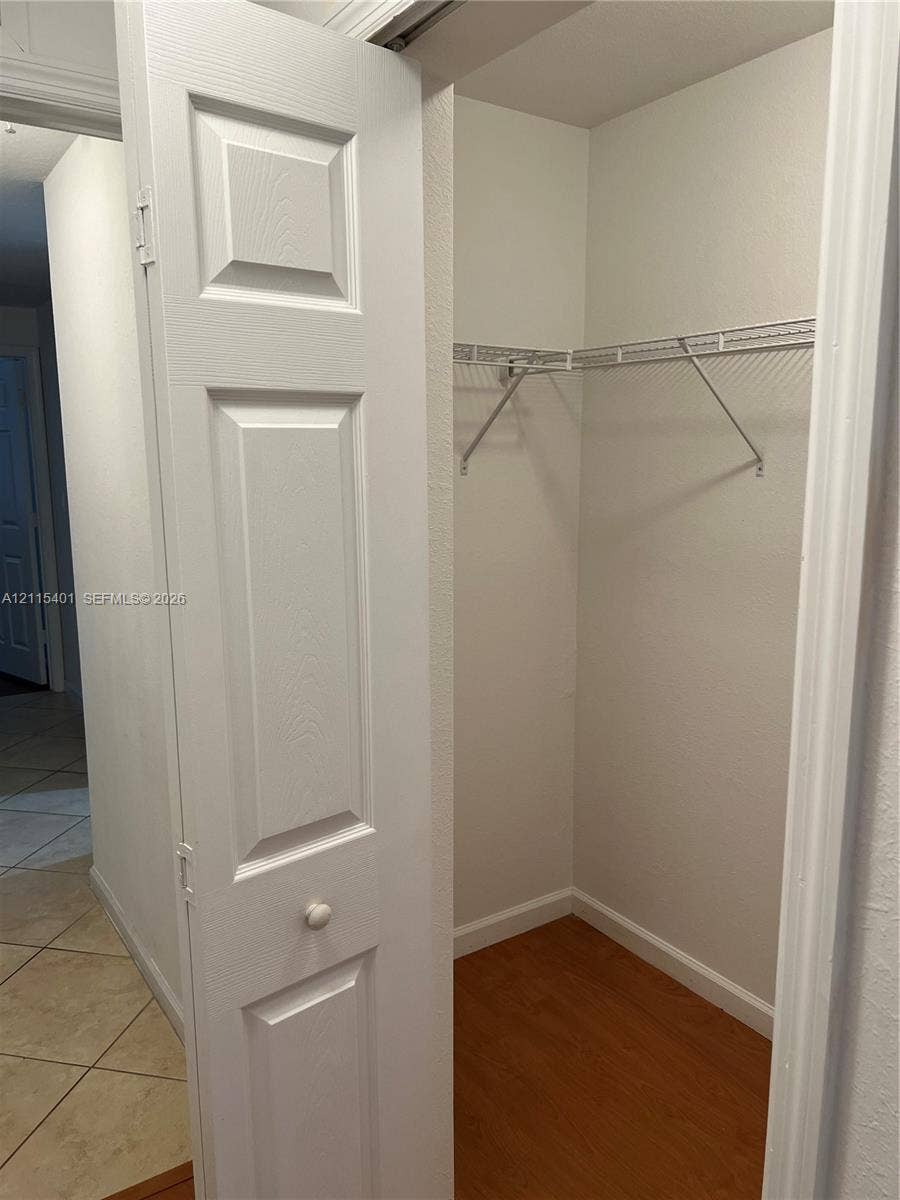 11503 NW 89th Street, #104, Doral, Doral, FL 33178 Storage closet featuring a white four-panel bi-fold door, wood-finish flooring, and white wire shelving