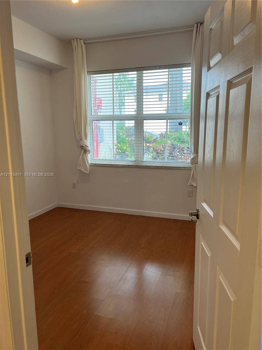 11503 NW 89th Street, #104, Doral, Doral, FL 33178 Room featuring wood-finish flooring, a large multi-pane window, and white interior walls