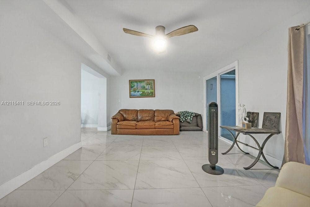 20302 NW 39th Court, Miami Gardens, FL 33055 Large-format neutral flooring with stone-pattern detail, sliding glass doors, and a ceiling fan with integrated lighting