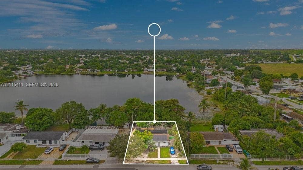 20302 NW 39th Court, Miami Gardens, FL 33055 Aerial perspective of a single-story residence situated on a waterfront lot featuring direct lake frontage, mature trees, and a concrete driveway