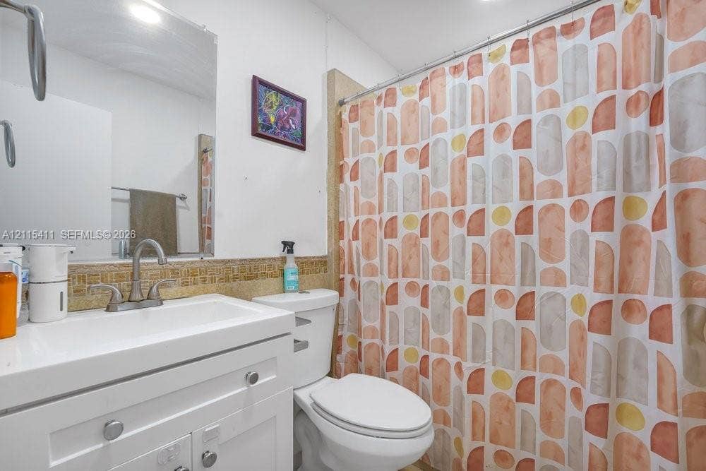 20302 NW 39th Court, Miami Gardens, FL 33055 White vanity cabinet featuring a rectangular integrated sink, arched-neck faucet, mosaic tile backsplash, and a wall-mounted mirror
