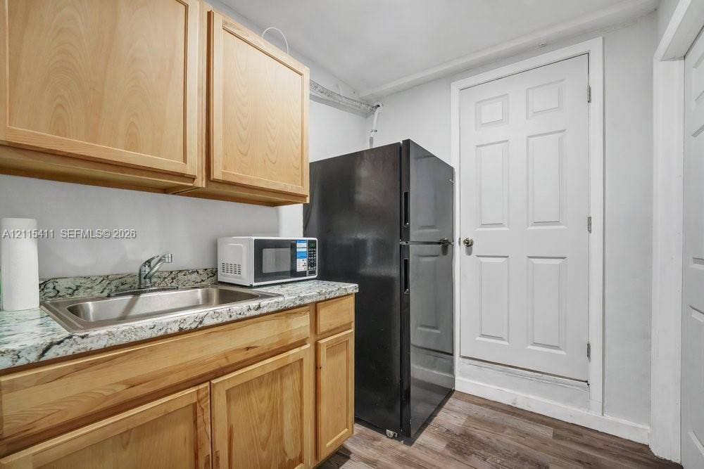 20302 NW 39th Court, Miami Gardens, FL 33055 Light wood cabinetry with integrated storage, stone-finish countertops, stainless steel sink, and wood-finish flooring