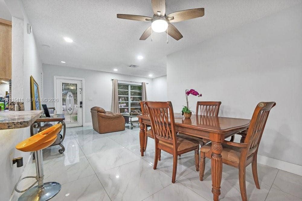 20302 NW 39th Court, Miami Gardens, FL 33055 Large-format tile flooring, recessed lighting, ceiling fan with integrated light fixture, and exterior door with a decorative glass insert