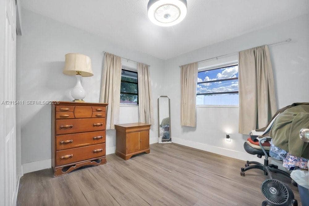 20302 NW 39th Court, Miami Gardens, FL 33055 Neutral interior featuring wood-finish flooring, two horizontal-slider windows, and a flush-mount ceiling light fixture
