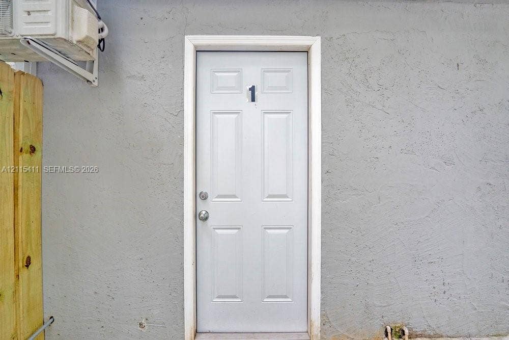 20302 NW 39th Court, Miami Gardens, FL 33055 Six-panel exterior door with metallic hardware, set within a light-toned stucco wall