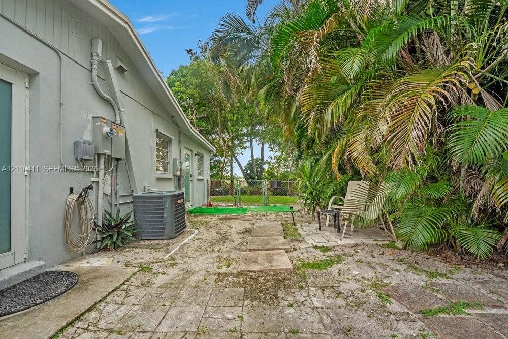 20302 NW 39th Court, Miami Gardens, FL 33055 Exterior space featuring concrete paver hardscaping, mature palm trees, and perimeter fencing