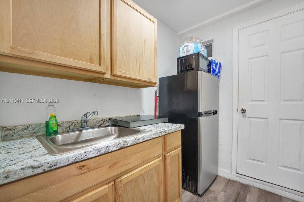 20302 NW 39th Court, Miami Gardens, FL 33055 Natural wood-finish cabinetry, speckled stone-finish countertop, stainless steel undermount sink with gooseneck faucet, and six-panel interior door
