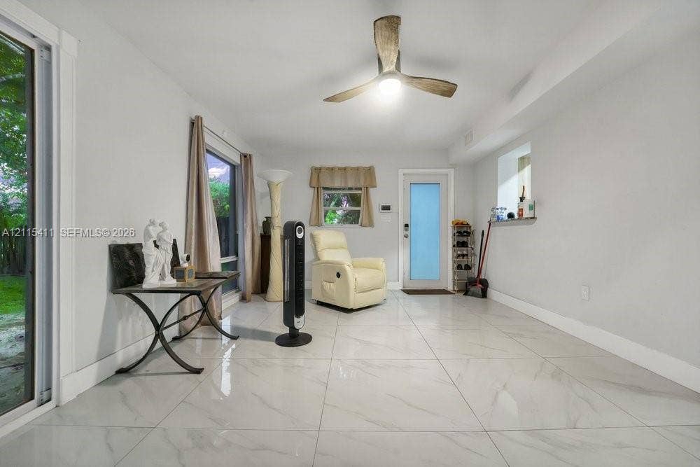 20302 NW 39th Court, Miami Gardens, FL 33055 Large-format tile flooring with a neutral finish, multi-blade ceiling fan with integrated light, glass-paneled exterior door, and sliding glass door with external exposure