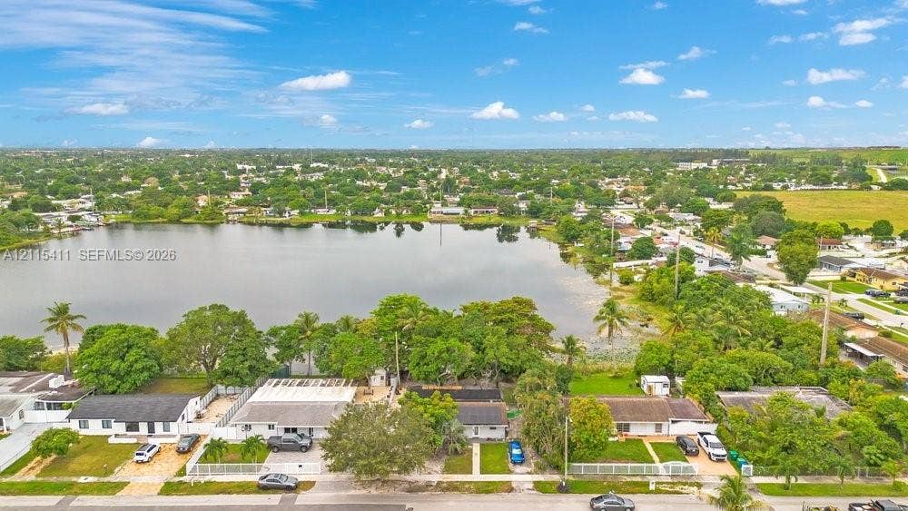 20302 NW 39th Court, Miami Gardens, FL 33055 Aerial perspective featuring residential structures situated along a lakefront, incorporating paved driveways, fenced perimeters, and established mature trees