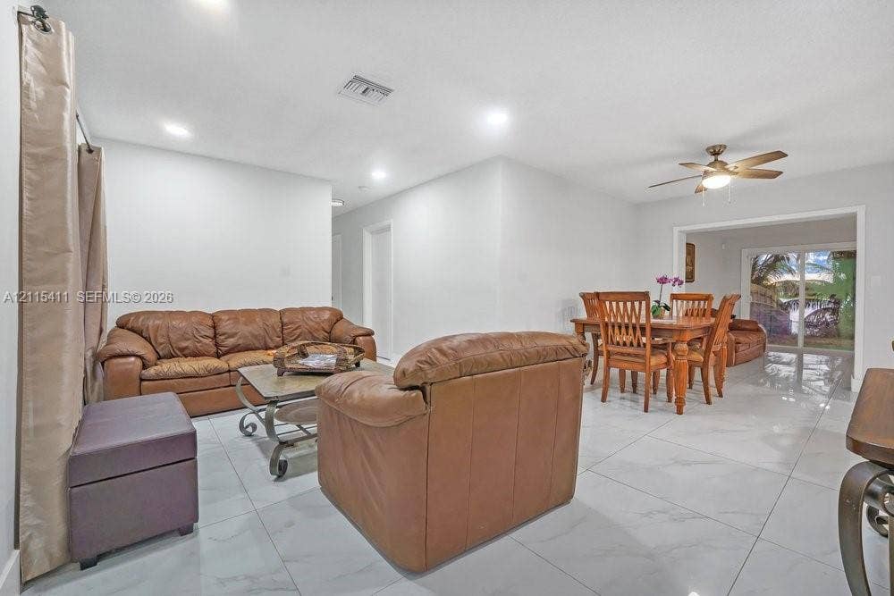20302 NW 39th Court, Miami Gardens, FL 33055 Large-format neutral tile flooring, recessed ceiling lighting, and a ceiling fan with integrated light fixture, featuring glass sliding doors leading to an outdoor space