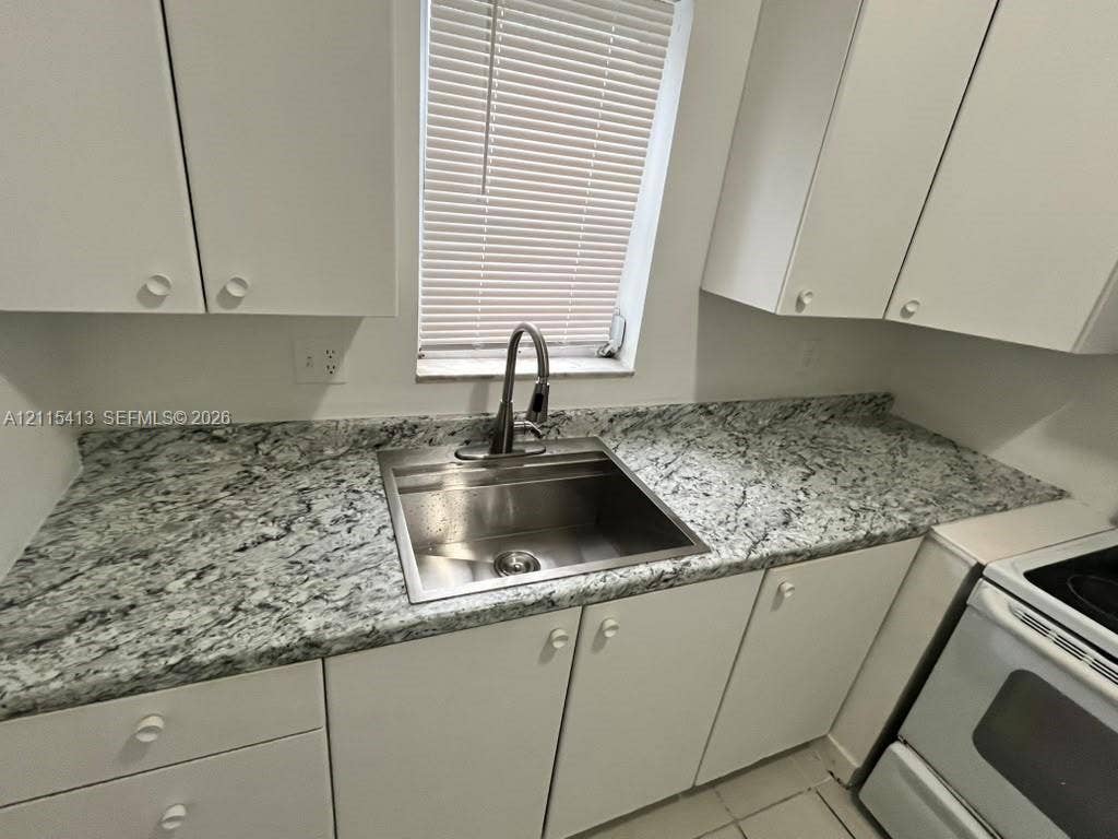 3001 NW 4th Terrace, #173, Pompano Beach, Pompano Beach, FL 33064 Kitchen featuring stone-patterned countertops, stainless steel undermount sink, high-arc pull-down faucet, white cabinetry, and window with blinds